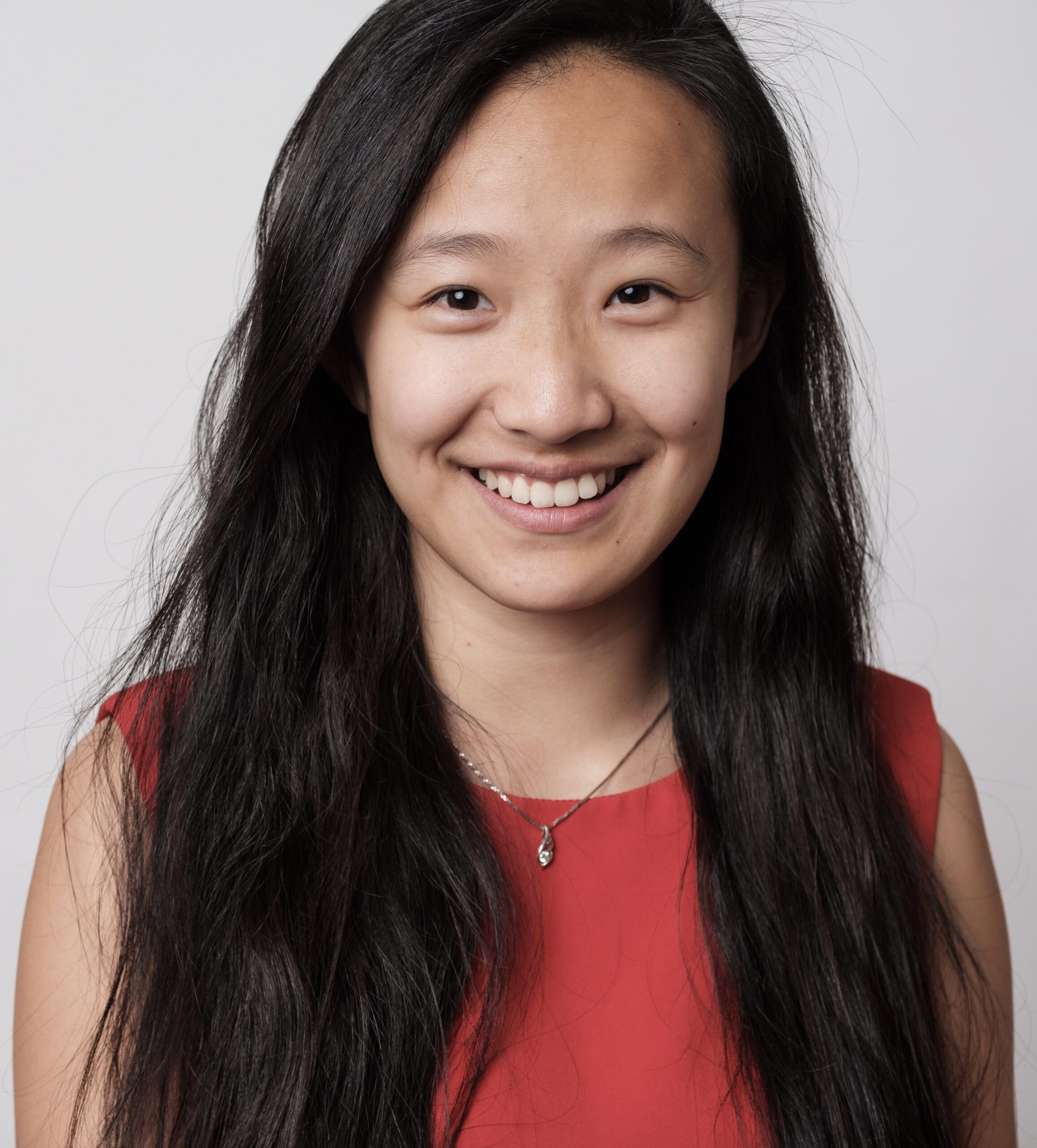 Shuo Chen smiles for a professional headshot, wearing a red shirt against a neutral white background